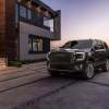 The 2023 GMC Yukon Denali Ultimate exterior in front of a modern building at dusk.