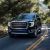 The 2023 GMC Yukon driving on a wooded road.
