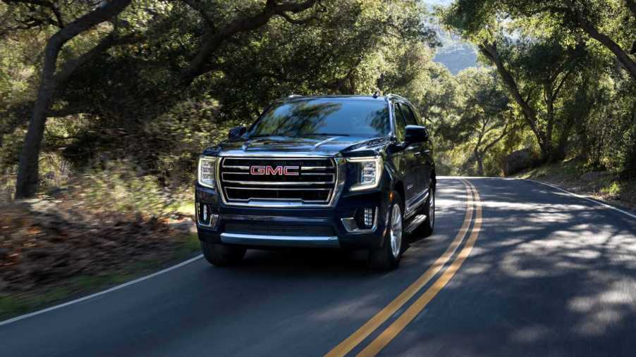 The 2023 GMC Yukon driving on a wooded road.