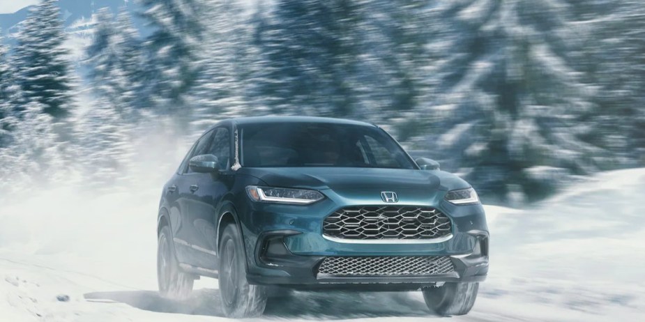A blue 2023 Honda HR-V subcompact SUV is driving in the snow. 