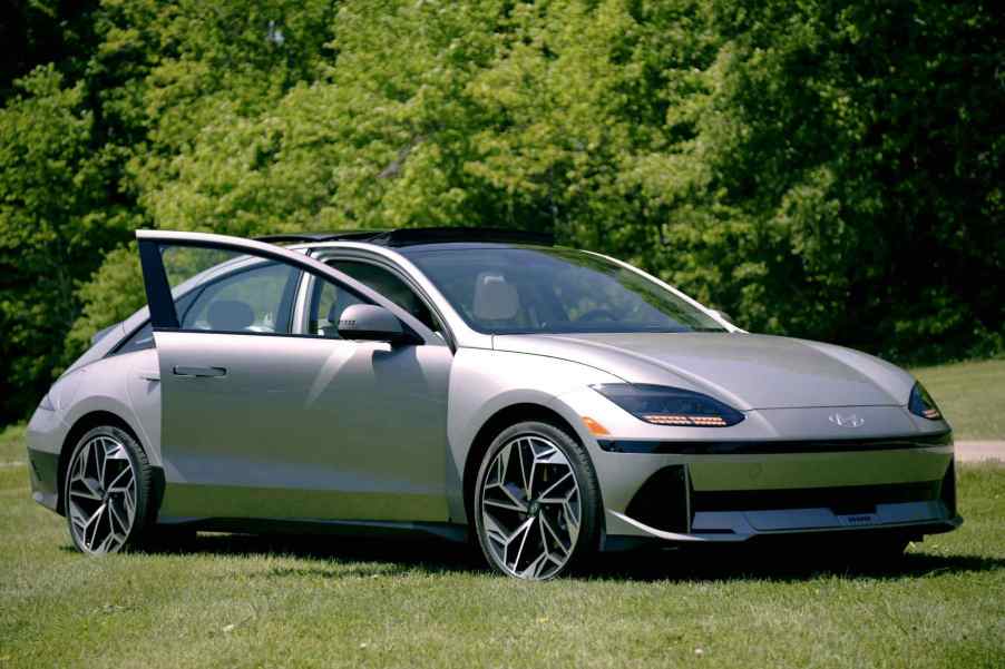 A silver 2023 Hyundai Ioniq 6 sits in front of green trees.