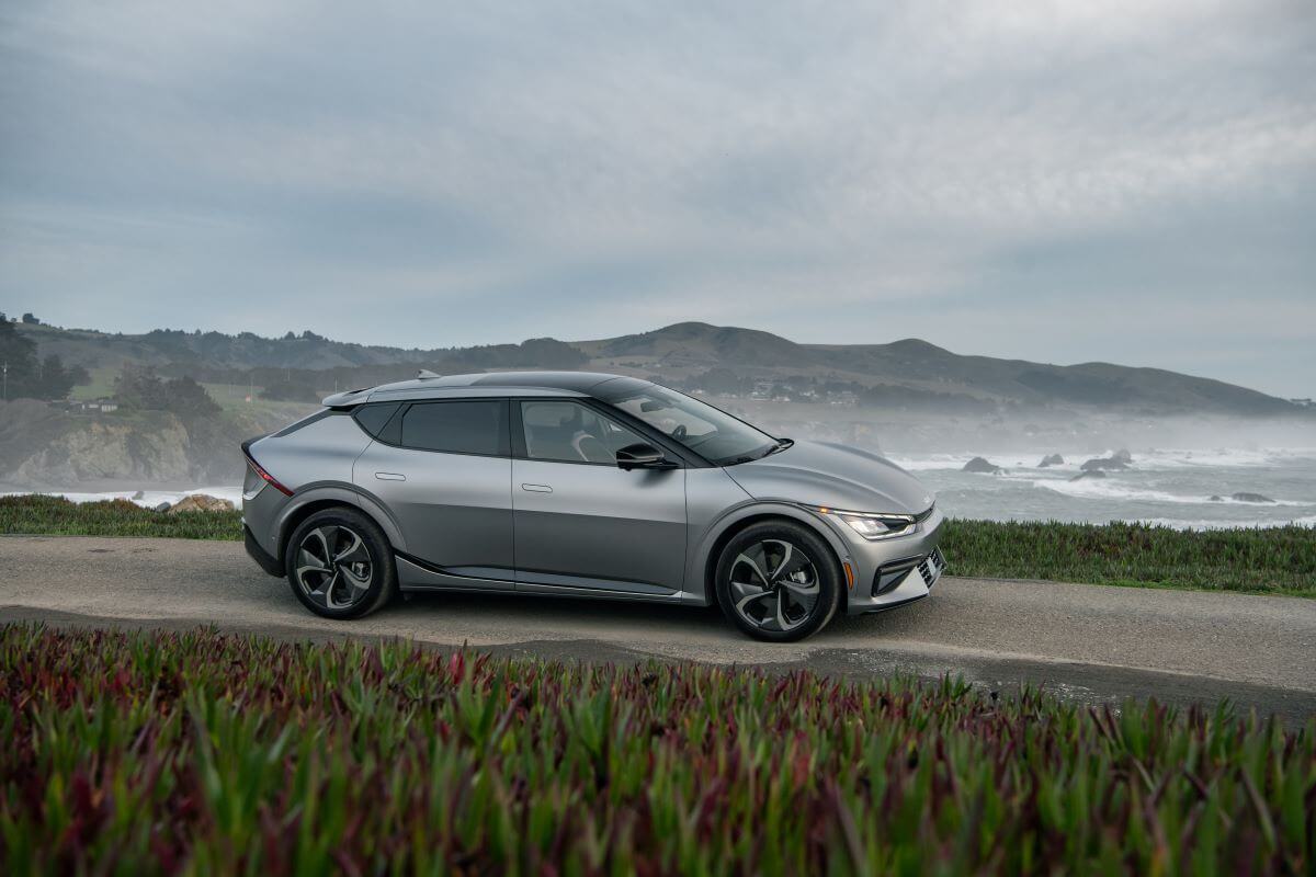 A gray 2023 Kia EV6 electric compact SUV model parked on a hill overlooking foggy sea water