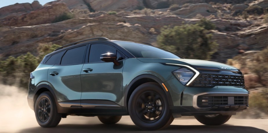 A green 2023 Kia Sportage small SUV is driving off-road. 