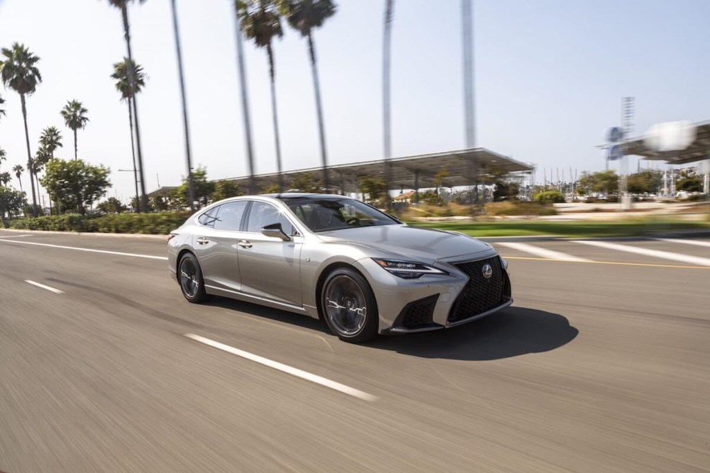 A silver 2023 Lexus LS 500 driving down a tropical highway