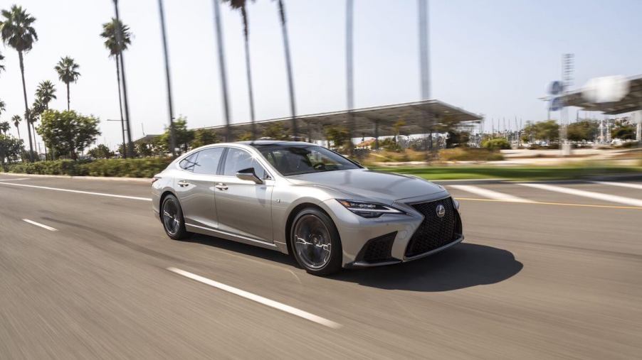 A silver 2023 Lexus LS 500 driving down a tropical highway