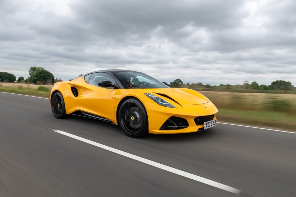A bright yellow Lotus Emira blasts down a country road. 