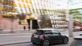 A black 2023 Mini Cooper S driving through downtown streets
