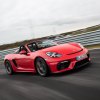 A red 2023 Porsche 718 Boxster driving on a track