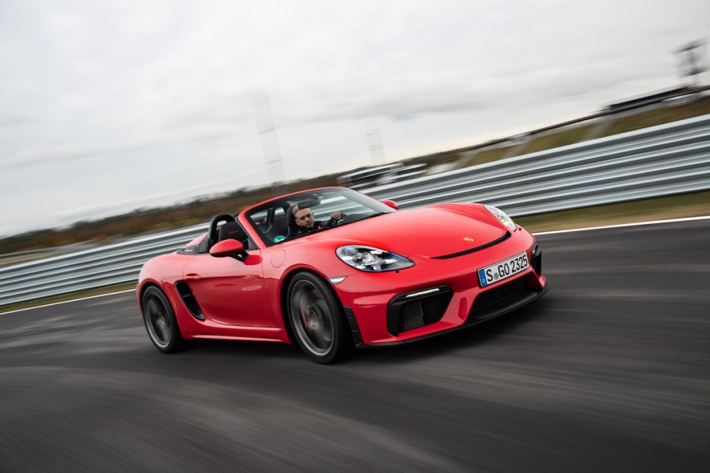 A red 2023 Porsche 718 Boxster driving on a track