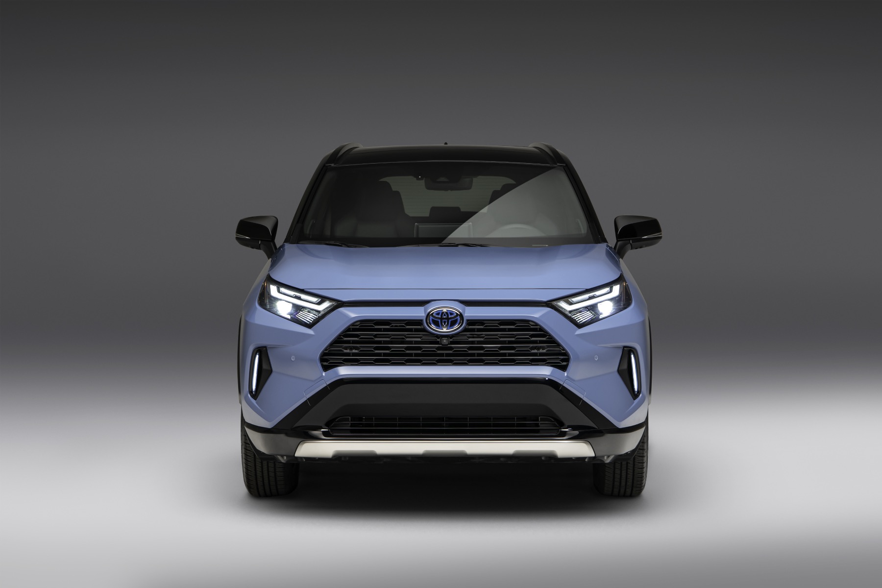 A blue 2023 Toyota RAV4 faces the camera directly with a grey studio background.