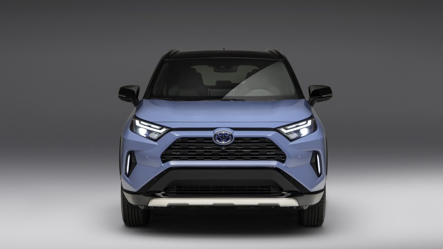 A blue 2023 Toyota RAV4 faces the camera directly with a grey studio background.