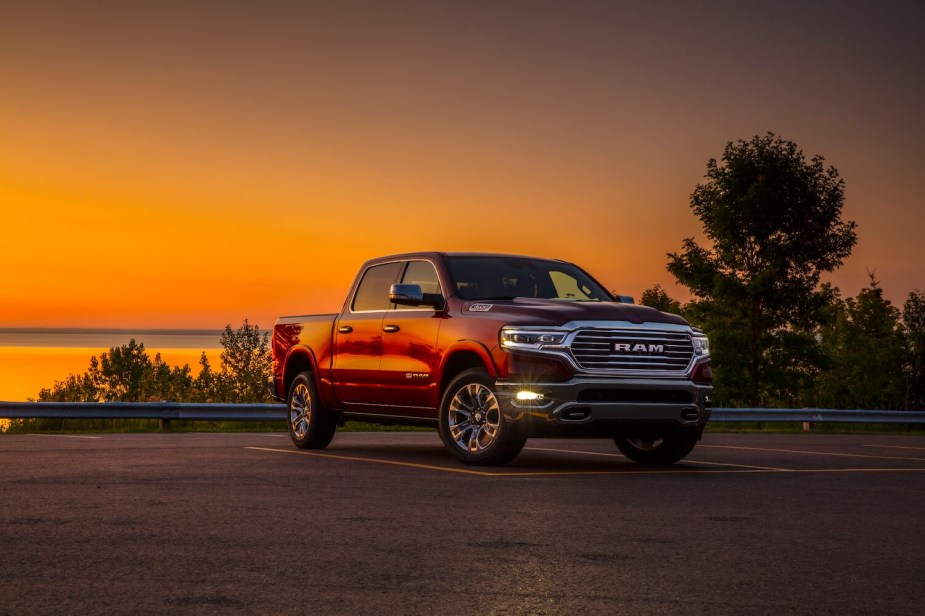 A 2023 Ram 1500 pickup truck with four-corner air suspension parked in front of a lake during a sunset.