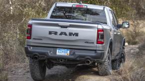 A silver Ram Rebel off-road pickup truck navigates an obstacle in a trail.