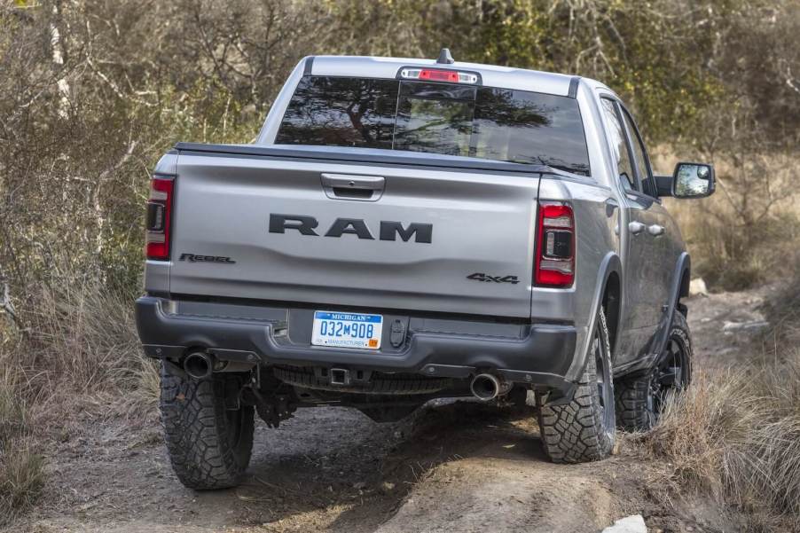A silver Ram Rebel off-road pickup truck navigates an obstacle in a trail.
