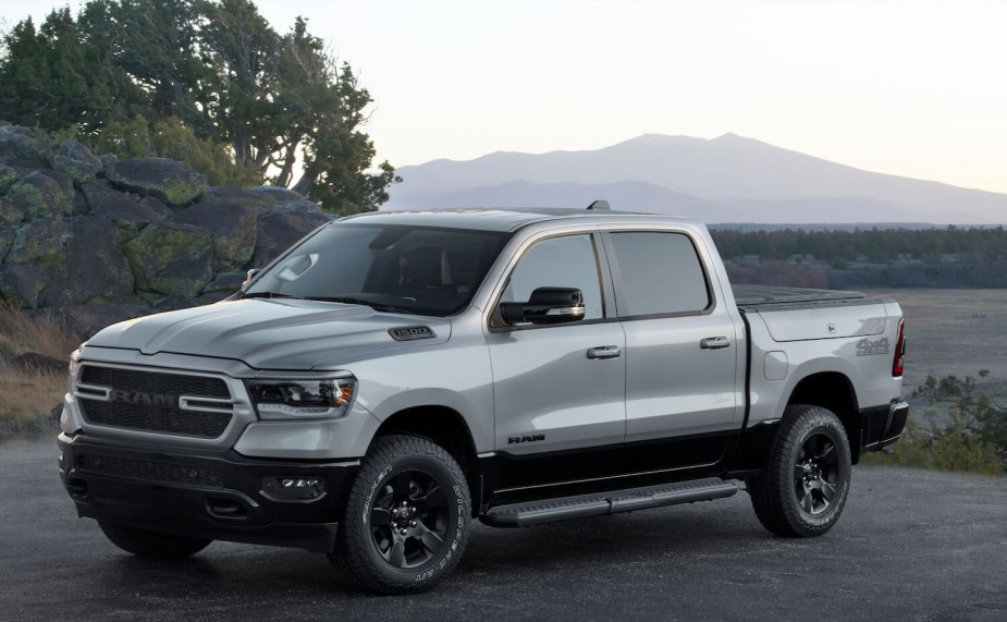 A light gray 2023 Ram 1500 hybrid eTorque pickup truck with blacked-out badging, parked in front of a mountain range.