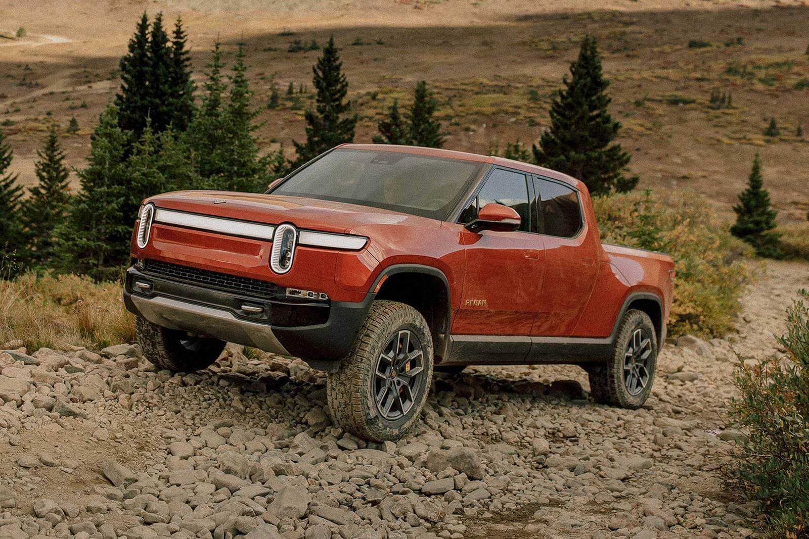 The 2023 Rivian R1T off-roading over rocky terrain