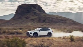 A white 2023 Toyota RAV4 driving off-road.