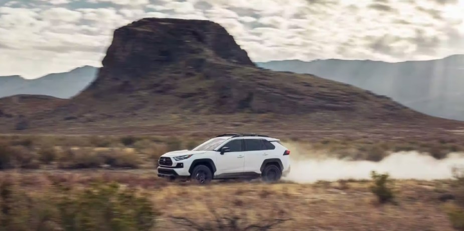 A white 2023 Toyota RAV4 small SUV is driving off-road. 