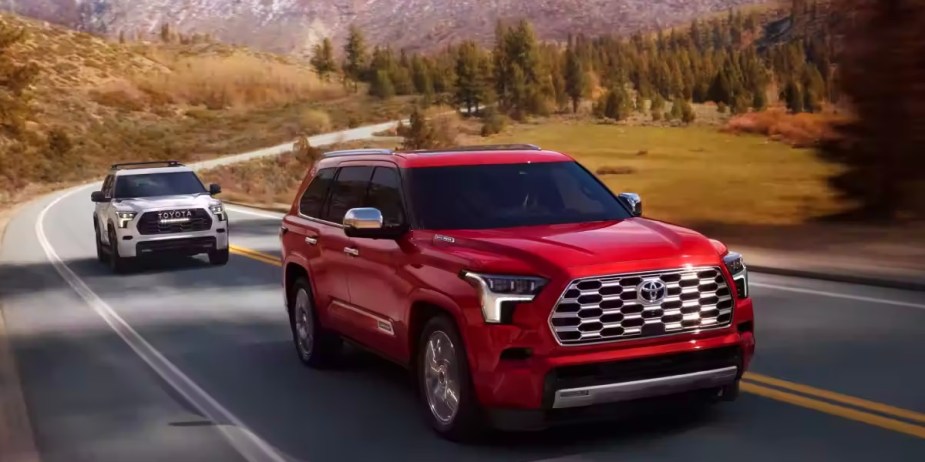 Two 2023 Toyota Sequoia full-size SUVs are driving on the road. 