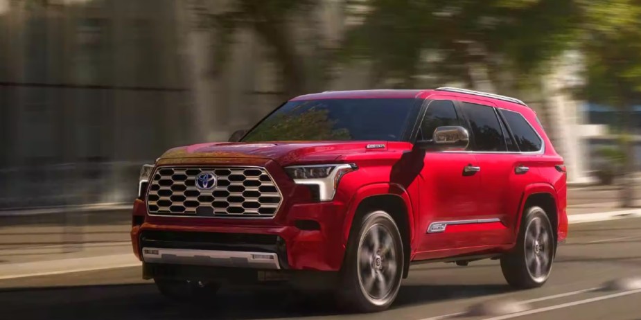 A red 2023 Toyota Sequoia full-size SUV is driving on the road. 