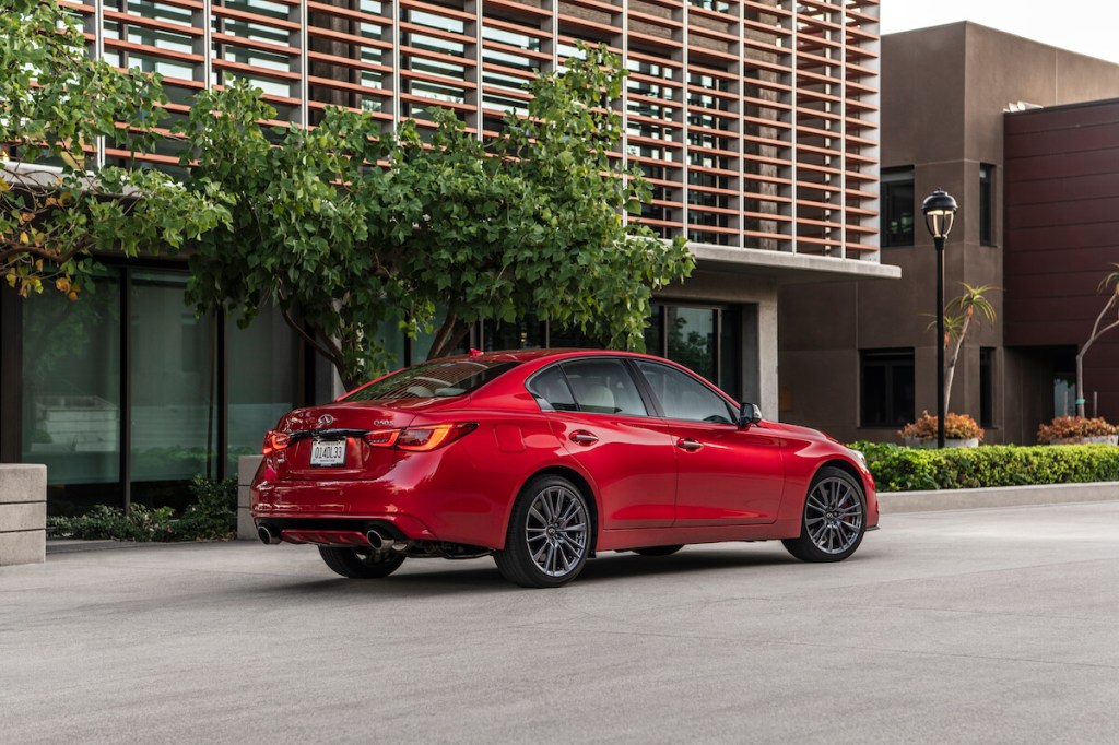 A red 2023 Infiniti Q50S rear end parked next to a building