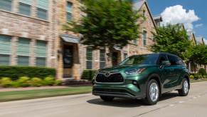 A green 2023 Toyota Highlander driving down a city street