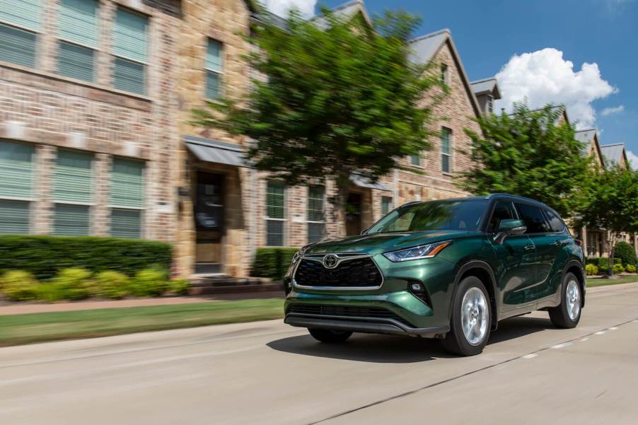 A green 2023 Toyota Highlander driving down a city street