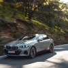 A Gray 2024 BMW 5 Series driving down a forest road