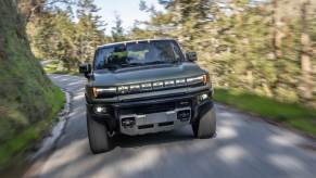 The 2024 GMC Hummer EV driving down a road in the forest.