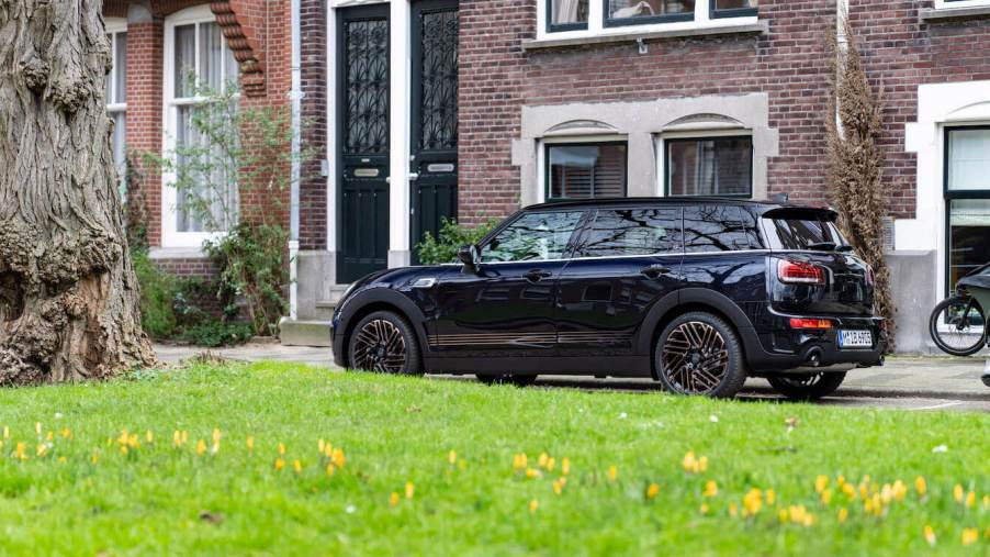 The black 2024 Mini Clubman in front of a building with green grass next to it.