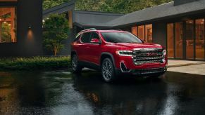 A red GMC Acadia in the rain. The GMC Acadia has three common problems that owners report. Is it reliable?