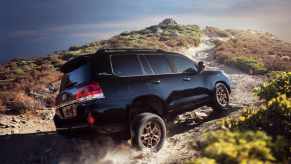 A black 2021 Toyota Land Cruiser climbs up an off-road trail. The Land Cruiser was discontinued in America after the 2021 model year.