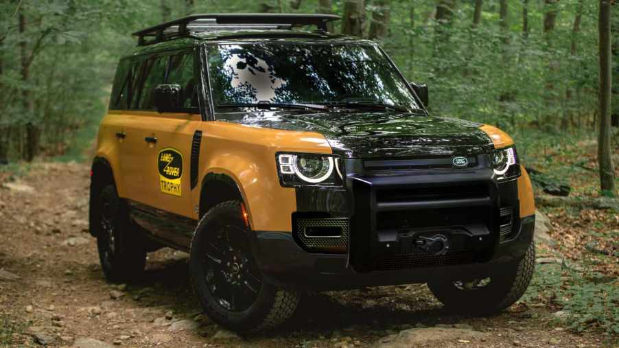The Land Rover Defender Trophy Edition sits in a green forest. It's a new off-road SUV on the market.