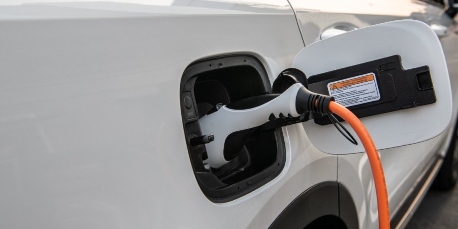 A white 2023 Kia Sportage Plug-In Hybrid is charging.