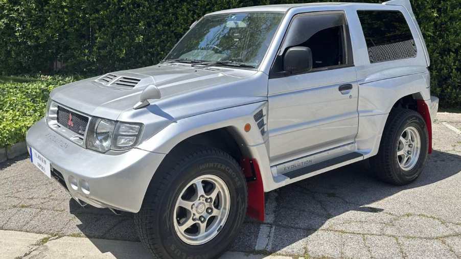 A silver Mitsubishi Pajero Evolution sits on sunny tarmac. The Pajero Evolution was a 90s 4x4 SUV homologated for off-road racing.