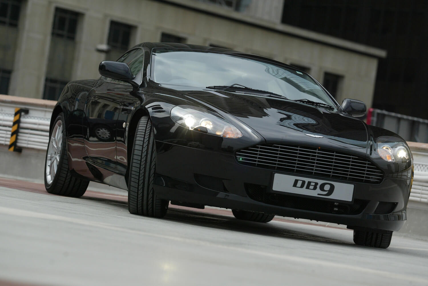 A black Aston Martin DB9 car in a parking lot.