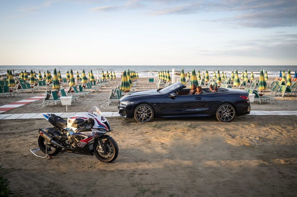 A BMW S 1000 RR motorcycle and M4 park at the beach. 