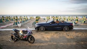 A BMW S 1000 RR motorcycle and M4 park at the beach.