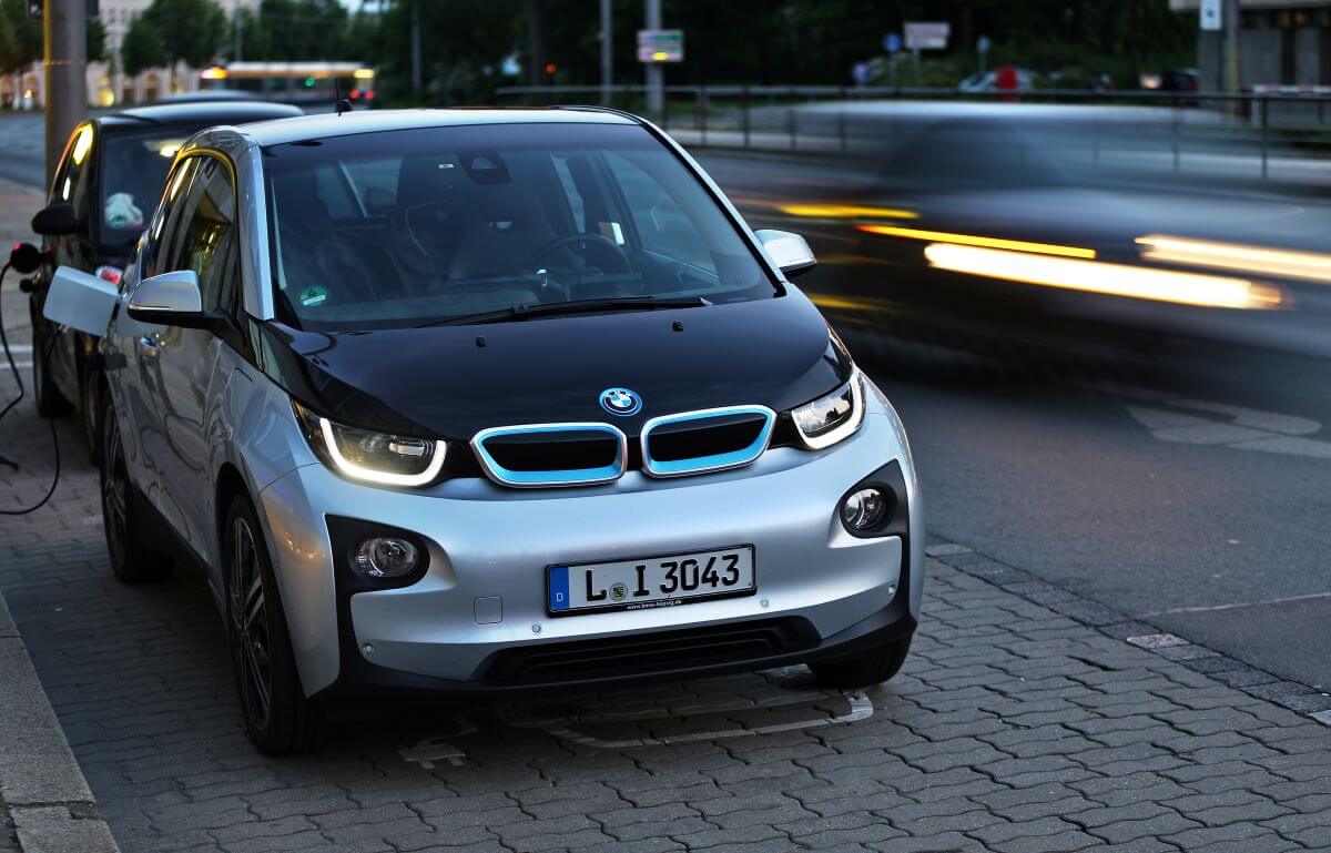 A BMW i3 plugged into a charging station, which is offered with an available engine range extender