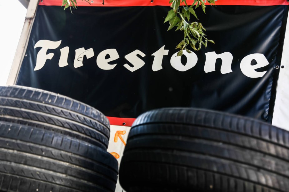 A stack of tires in front of a Firestone sign.