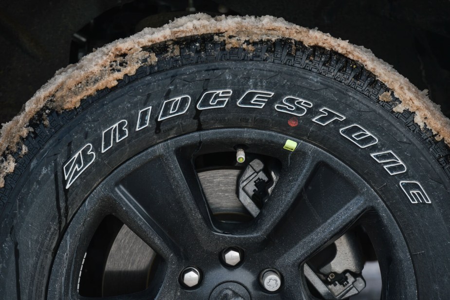 A Bridgestone tire on a parked car, covered in slushy snow.