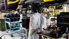 Mechanics assemble a car in a factory.