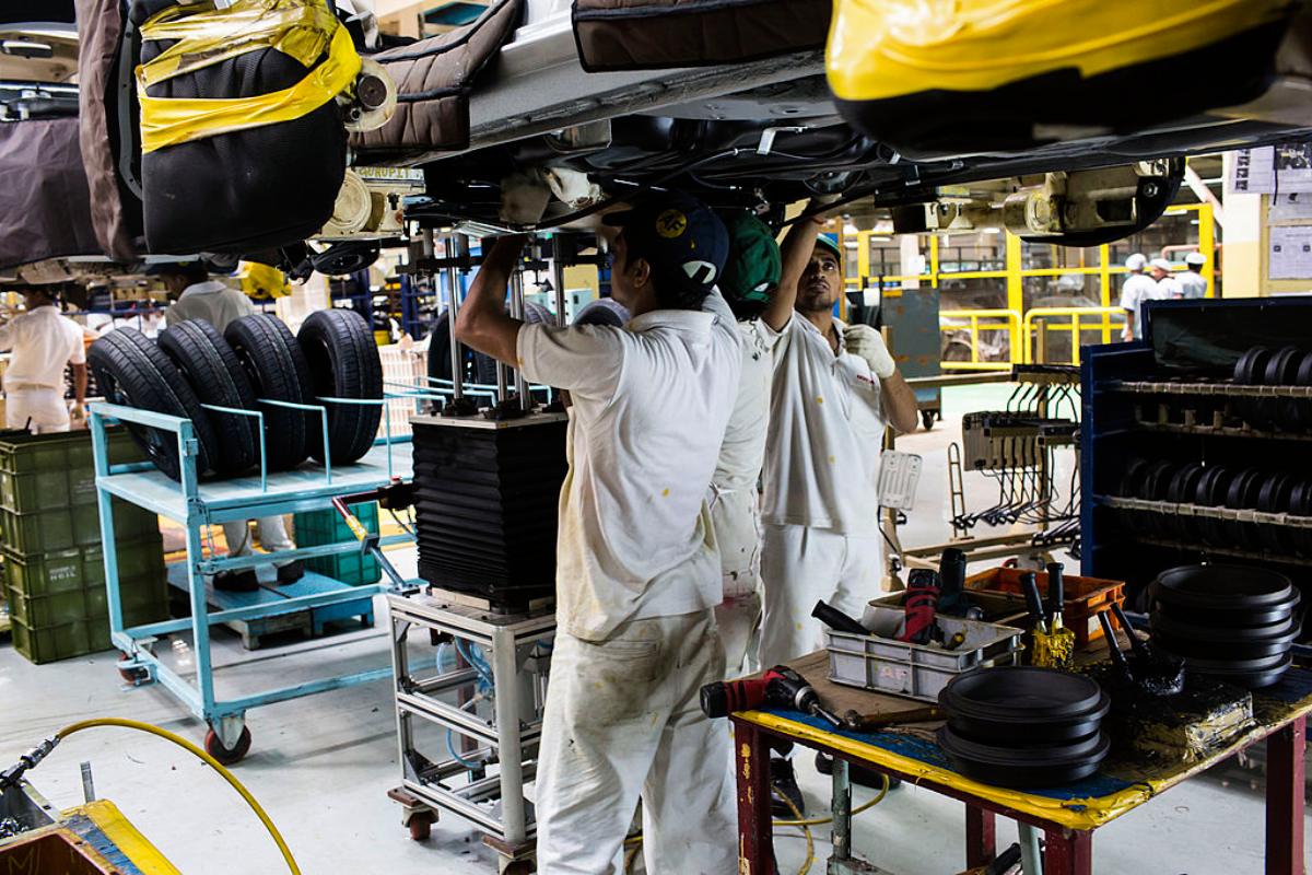 Mechanics assemble a car in a factory.