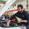 An auto mechanic completes an oil change on a customer's vehicle. Oil change is part of the maintenance schedule.