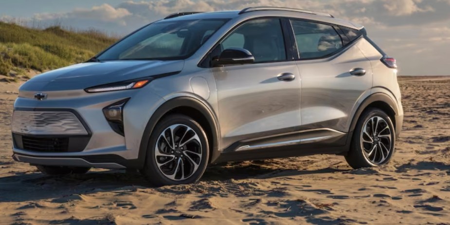 A gray 2023 Chevrolet Bolt EUV subcompact electric SUV is parked on the sand. 