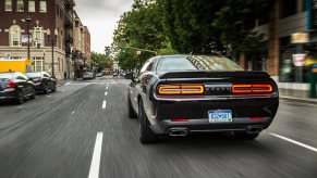 A new black Dodge Challenger R/T V8 blasts down a city street.