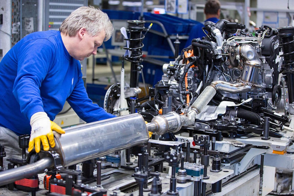 Factory worker installing exhaust system