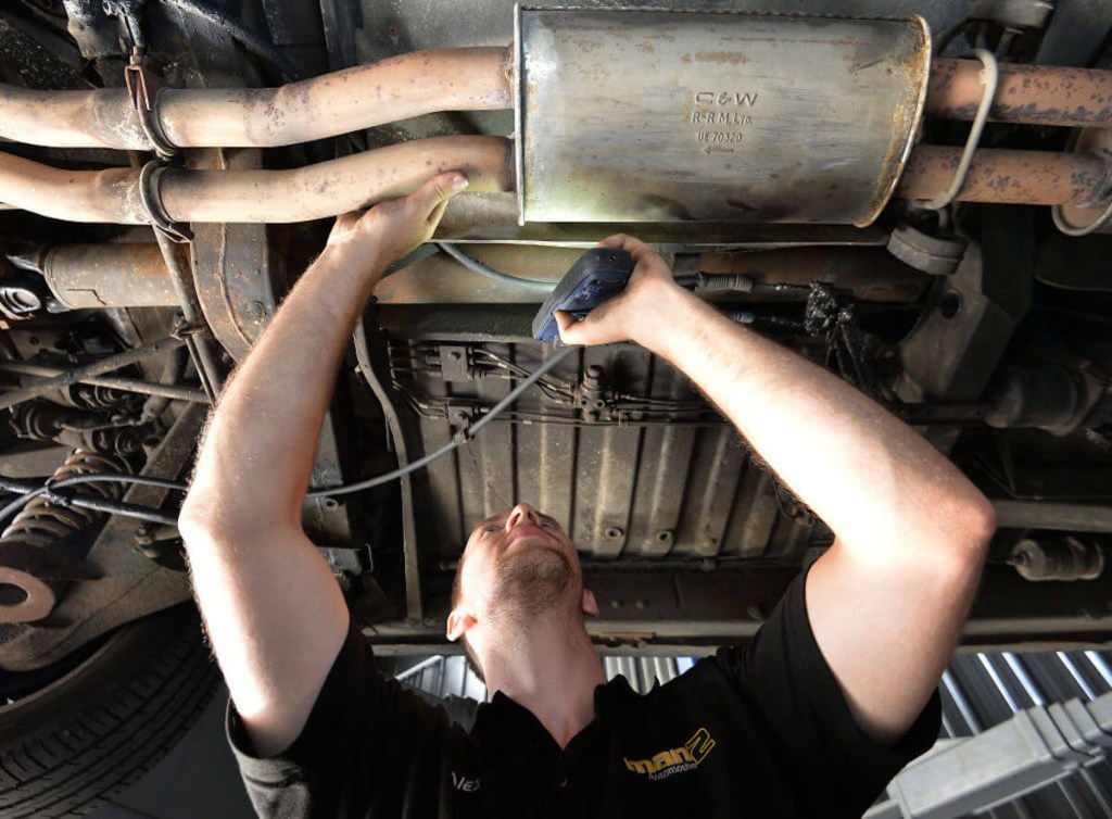 Technician inspecting exhaust system