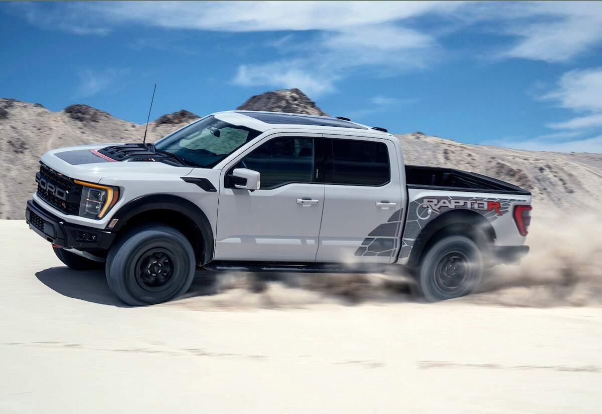 A gray 2023 Ford Lobo Raptor R kicking up sand as it travels along a dune