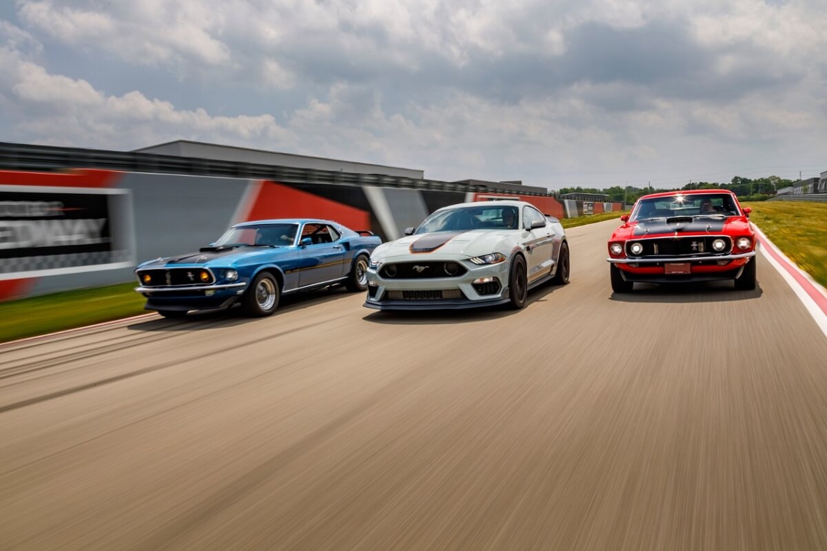 A series of Ford Mustang Mach 1 models cruise down a race track.